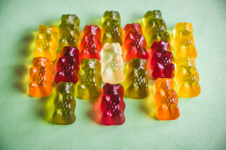 Colorful gummy bear candies on green background. Top view.の写真素材