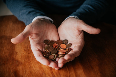 Hands of a man holding coins on a wooden table background.の写真素材