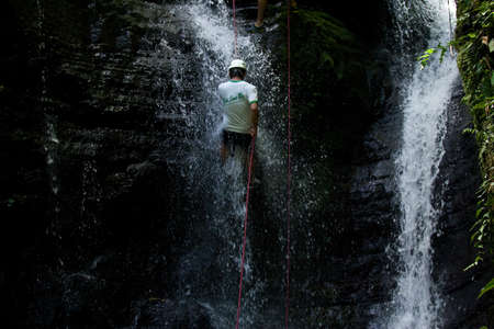 ZAMORA REGION, YANTZAZA, ECUADOR-May 11:Rappel student climbs down waterfall  in Yantzaza, Ecuador on May 11, 2013. Rappelling is part of a tourism class.のeditorial素材