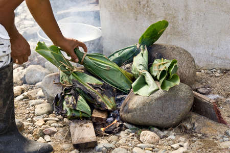 ZAMORA REGION, YANTZAZA, ECUADOR-Circa 2013  Cooking food wrapped in Banana Leaves on tradional fire with charred leaves Ecuador Circa 2013. Banana leaves are plentiful and used for disposable cookingのeditorial素材