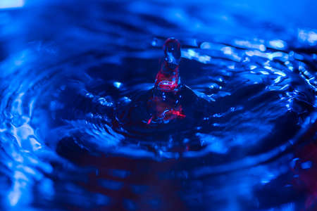 water drops falling on water with blue lights abstract emotion turmoilの写真素材