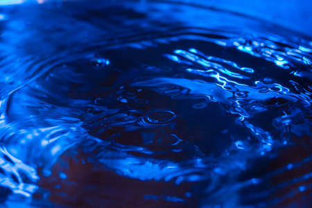 water drops falling on water with blue lights abstract emotion turmoilの写真素材