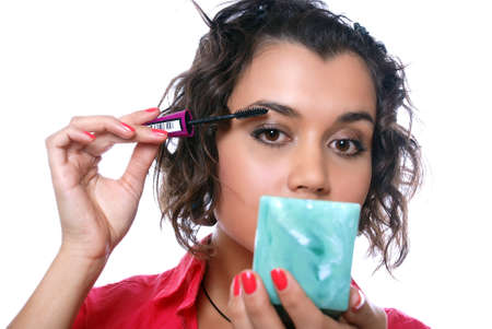 beauty girl looks in mirror and paints eyelashes with black inkの写真素材