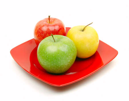 A close up of a  red plate with juicy green yellow and red appleの写真素材
