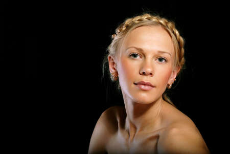 Portrait of a blonde girl with a braid on black backgroundの写真素材