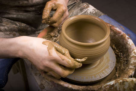 The hands of a potter, creating an earthen jar on the circle, close-upの写真素材