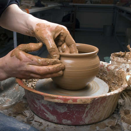 The hands of a potter, creating an earthen jar on the circle, close-upsの写真素材