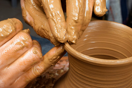 hands of a potter, creating an earthen jar on the circle
