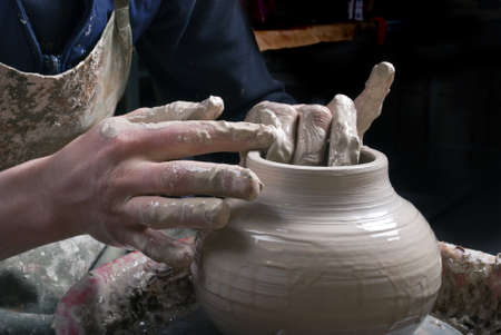 Potter at work creating clay bowl on turning wheelの写真素材