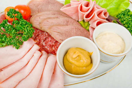 Cutting sausage and cured meat on a plateの写真素材