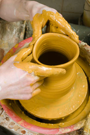 hands of a potter, creating an earthen jar of white clayの写真素材