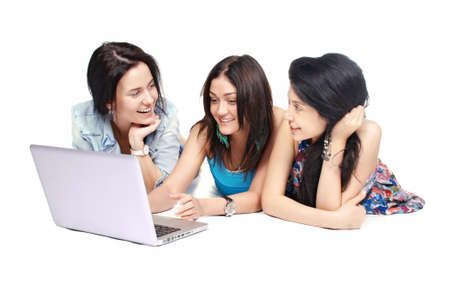 Three girls-students with laptop sitting on white backgroundの写真素材
