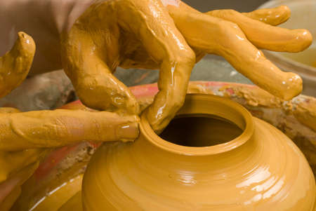 hands of a potter, creating an earthen jar of yellow clayの写真素材