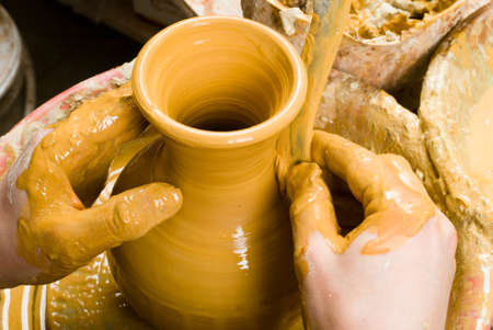 hands of a potter, creating an earthen jar of white clayの写真素材