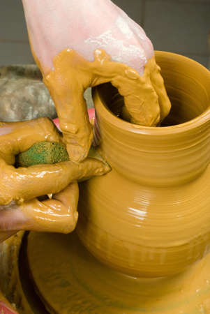 hands of a potter, creating an earthen jar of yellow clayの写真素材