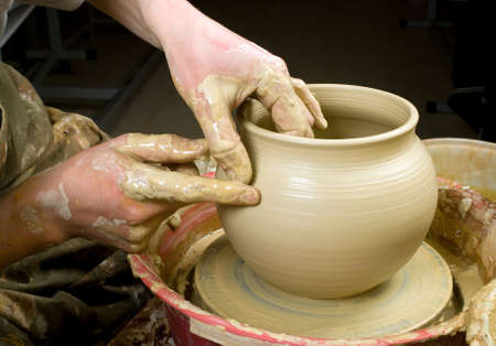 hands of a potter, creating an earthen jar of white clayの写真素材
