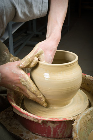 hands of a potter, creating an earthen jar on the circle