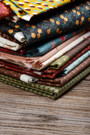 heap of cloth fabrics on wooden tableの写真素材