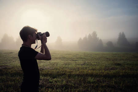 photographer in the fog taking a picture of the landscapeの写真素材