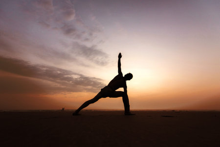 Man doing yoga on sunset. Ardha-Chandrasana. Side viewの写真素材