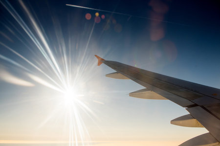 Wing of airplane in with sunrise and blue sky