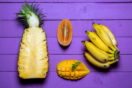 Fruits on a violet background. Pineapple, bananas, mango, melonの写真素材