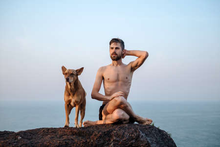 Healthy man practicing yoga under the beach at sunsetの写真素材