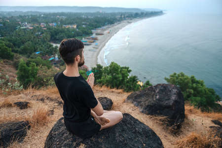 Healthy man practicing yoga under the beach at sunsetの写真素材