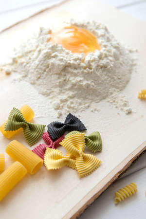 Different kinds of pasta on a wooden background. Farfalle, fettuccine, noodles, fusilli and penne rigate.の写真素材