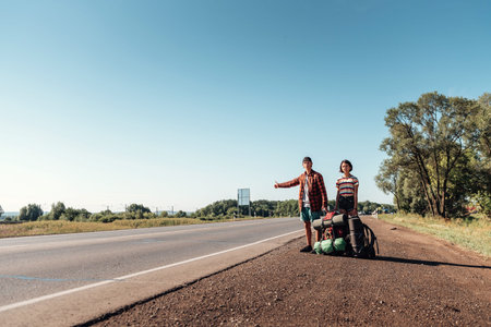 Hitchhiking couple. Backpackers on road.の写真素材