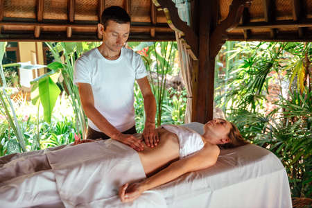 Master makes massage on the background of the gardenの写真素材