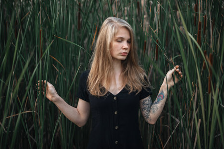 Romantic girl in black dress on green vegetative background.
