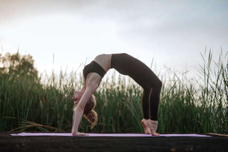 Girl practice yoga early morning on pier.の写真素材