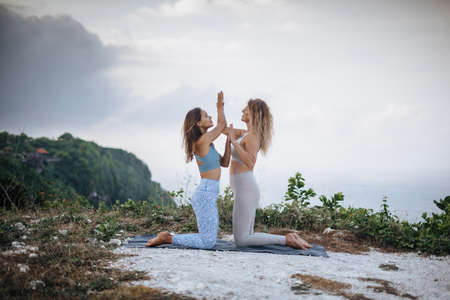 Pair of girls practice yoga against the background of the ocean.の写真素材
