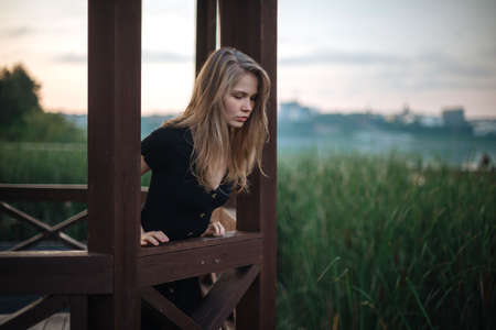 Romantic girl in black dress walking on pier.の写真素材