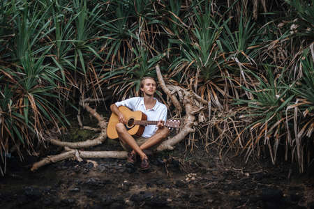 Romantic young man playing a guitar on the beachの写真素材