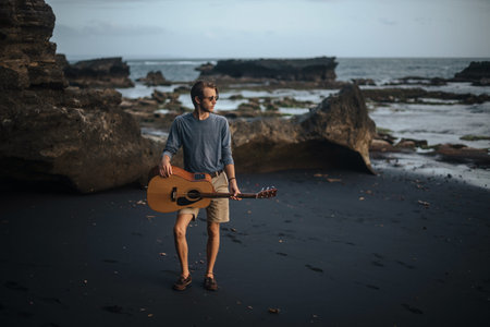 Romantic young man playing a guitar on the beachの写真素材