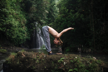 Yoga practice and meditation in nature. Man practicing near river.