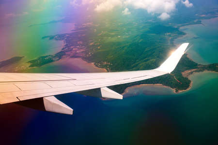 Wing of airplane in cloudy sky with rainbow effect.の写真素材