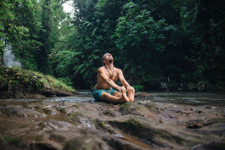 Yoga practice and meditation in nature. Man practicing near river.の写真素材
