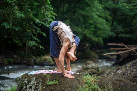 Yoga practice and meditation in nature. Man practicing near river.