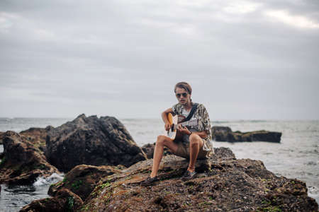 Romantic young man playing a guitar on the beachの写真素材