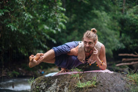 Yoga practice and meditation in nature. Man practicing near river.の写真素材