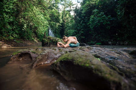 Yoga practice and meditation in nature. Man practicing near river.の写真素材