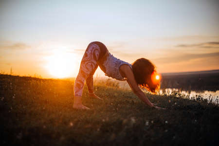 Yoga practice and meditation in nature in sunrise. Woman practicing near big river Kamaの写真素材
