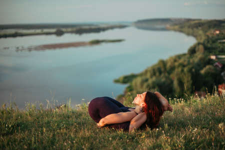Yoga practice and meditation in nature in sunrise. Woman practicing near big river Kamaの写真素材