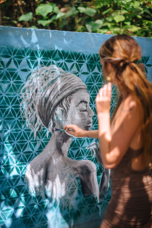 Girl make graffity on blue wall in Uduba, Indonesia. May 23, 2019.のeditorial素材