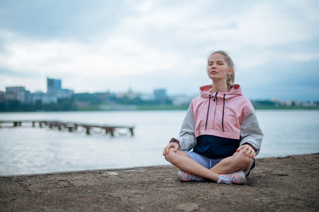 Yoga practice and meditation in nature in sunrise. Woman practicing near City on pier