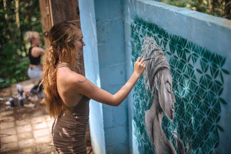 Girl make graffity on blue wall in Uduba, Indonesia. May 23, 2019.のeditorial素材