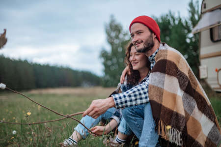 Romantic couple spending time together near trailer home. Handsome bearded man and beautiful woman enjoying company of each other. Traveling together with motor homeの写真素材